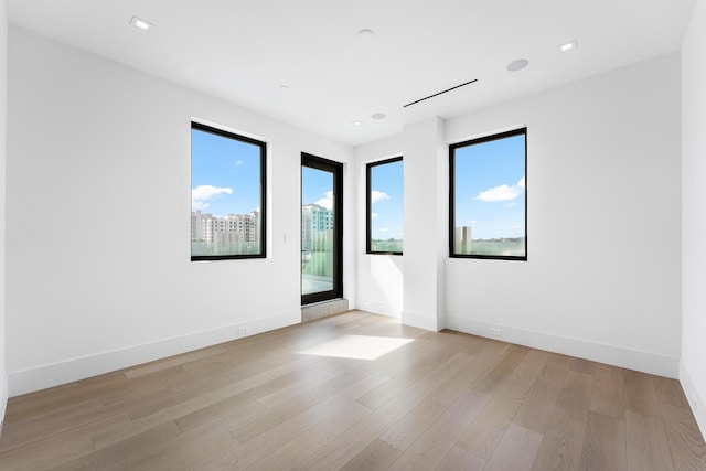 empty room with light wood-style flooring, baseboards, and recessed lighting