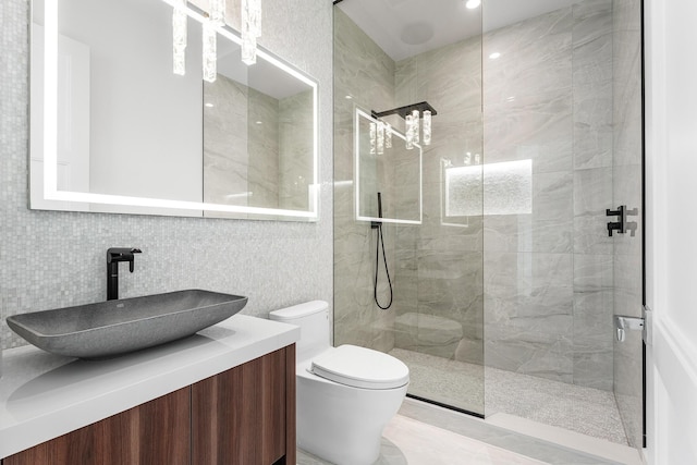 bathroom with toilet, vanity, decorative backsplash, and a walk in shower
