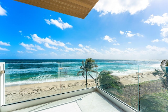 balcony with a water view and a view of the beach