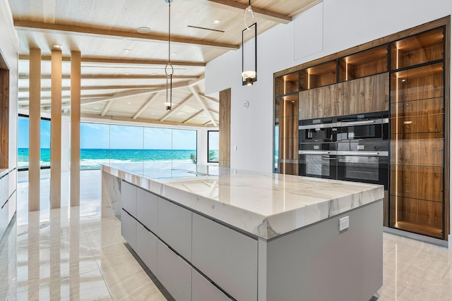 kitchen with white cabinetry, a kitchen island, beamed ceiling, light stone counters, and modern cabinets