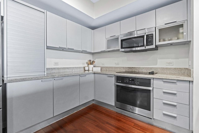 kitchen featuring dark wood-type flooring, light stone countertops, and appliances with stainless steel finishes