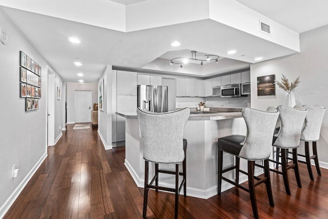 kitchen featuring dark hardwood / wood-style flooring, a breakfast bar, and appliances with stainless steel finishes