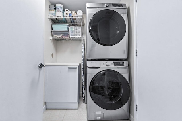 laundry room with stacked washer / dryer and light tile patterned flooring