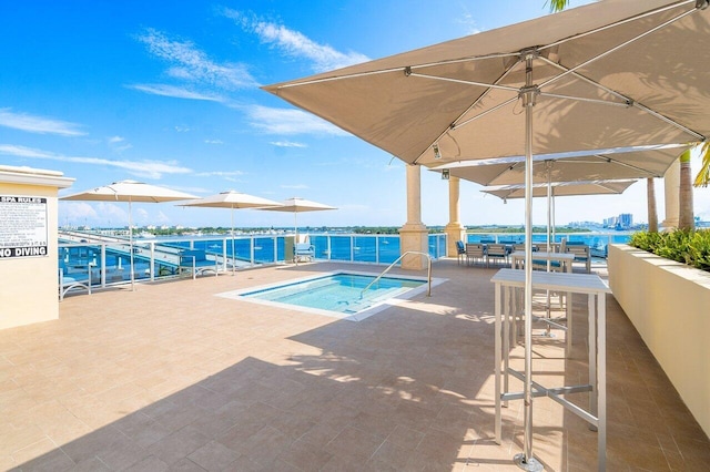 view of pool featuring a patio, a water view, and a hot tub