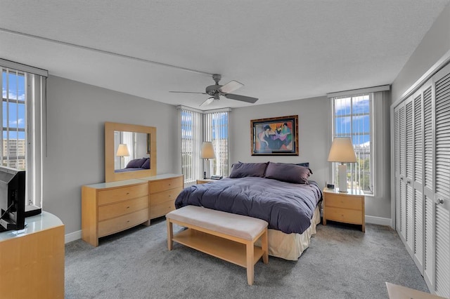 bedroom with light colored carpet, multiple windows, a closet, and ceiling fan