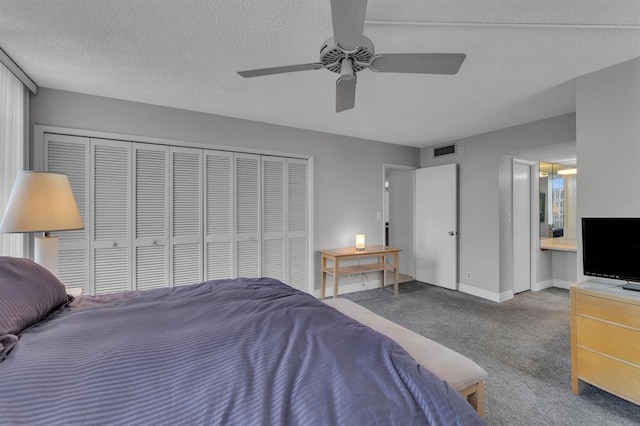 bedroom with ceiling fan, a textured ceiling, connected bathroom, carpet floors, and a closet