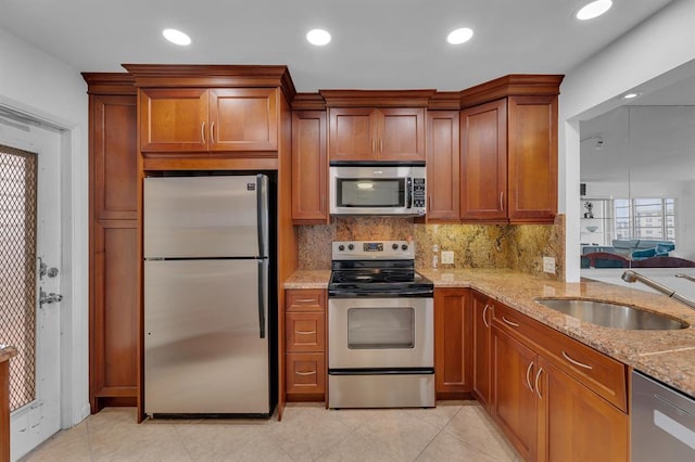 kitchen with stainless steel appliances, backsplash, sink, light tile patterned flooring, and light stone counters