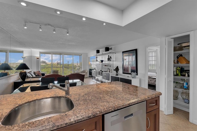 kitchen featuring light tile patterned flooring, sink, dishwasher, rail lighting, and light stone counters