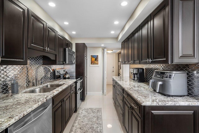 kitchen with appliances with stainless steel finishes, sink, light tile patterned floors, and decorative backsplash