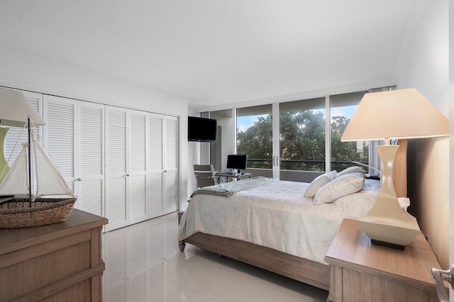 tiled bedroom featuring expansive windows, crown molding, and a closet