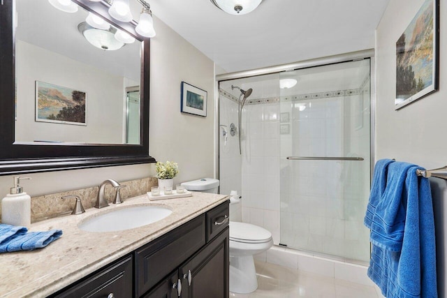 bathroom with vanity, a shower with shower door, tile patterned floors, and toilet