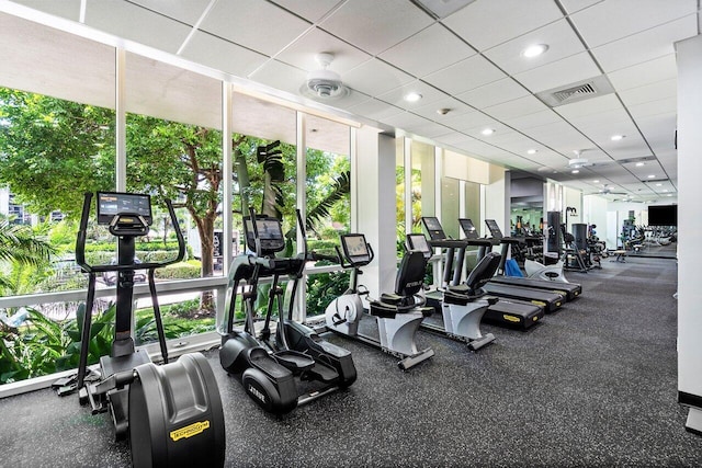 gym with floor to ceiling windows and a drop ceiling