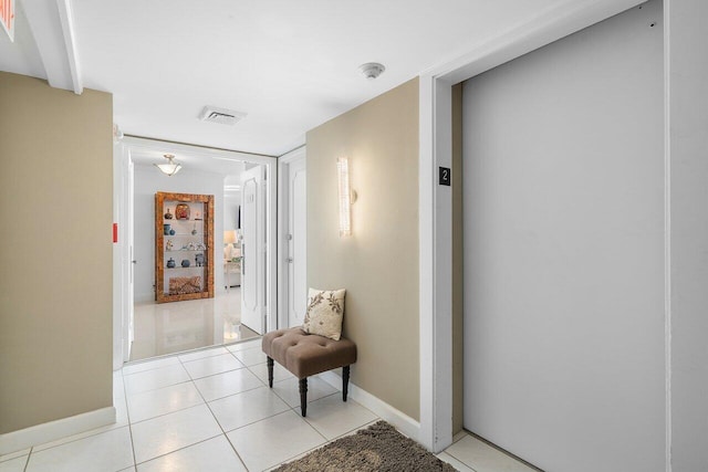 corridor featuring light tile patterned flooring and elevator