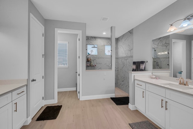 bathroom featuring hardwood / wood-style flooring, vanity, and a tile shower