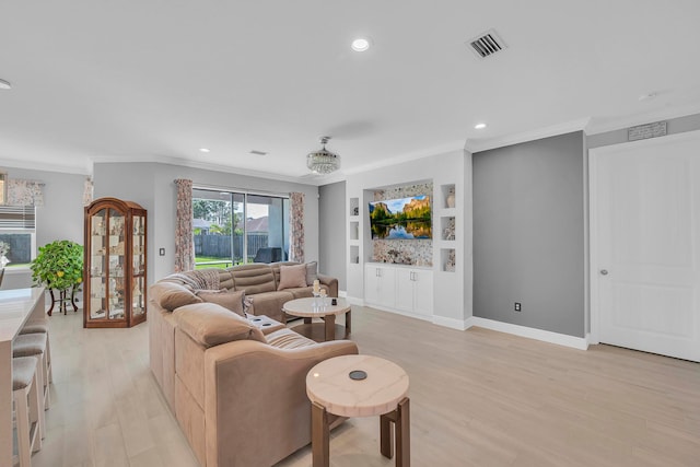 living room featuring built in shelves, light hardwood / wood-style floors, and crown molding