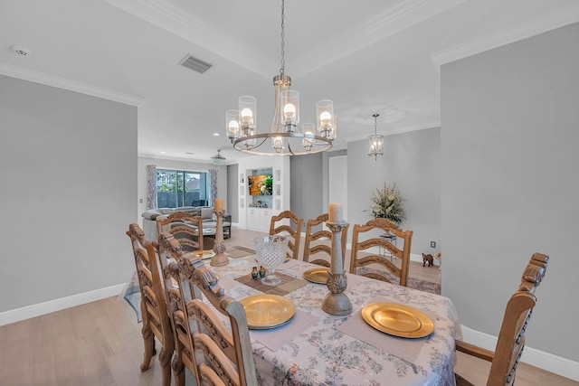 dining room with a notable chandelier, light hardwood / wood-style floors, and crown molding