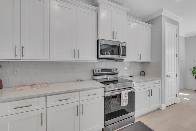 kitchen with stainless steel appliances, light hardwood / wood-style floors, tasteful backsplash, crown molding, and white cabinets