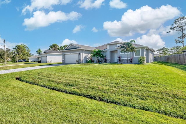 view of front of house featuring an attached garage, a front lawn, fence, stucco siding, and driveway