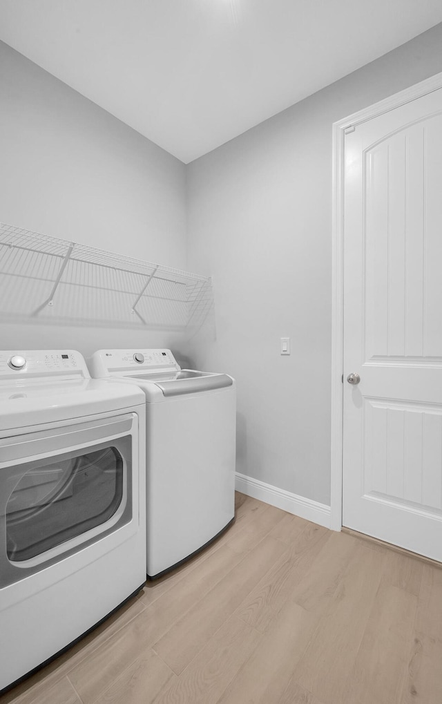 laundry room featuring washing machine and clothes dryer and light wood-type flooring