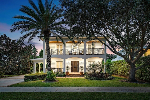 view of front of property featuring a porch, a balcony, and a lawn