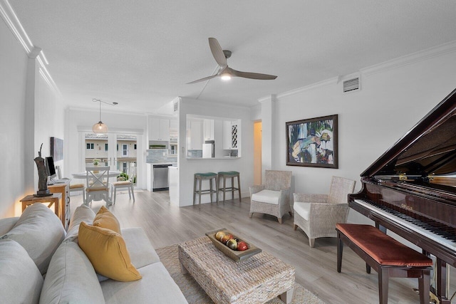 living room with a textured ceiling, light hardwood / wood-style floors, ceiling fan, and ornamental molding