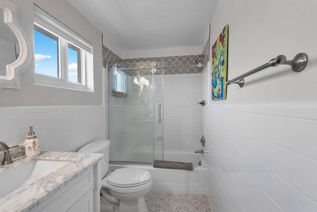 full bathroom featuring vanity, enclosed tub / shower combo, tile walls, and toilet