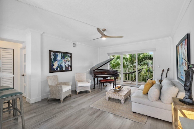 living room featuring a textured ceiling, ceiling fan, light hardwood / wood-style floors, and crown molding