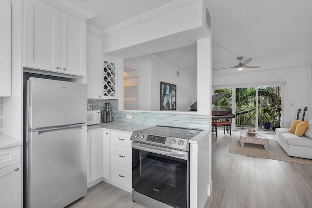 kitchen featuring white cabinetry, tasteful backsplash, electric stove, and fridge