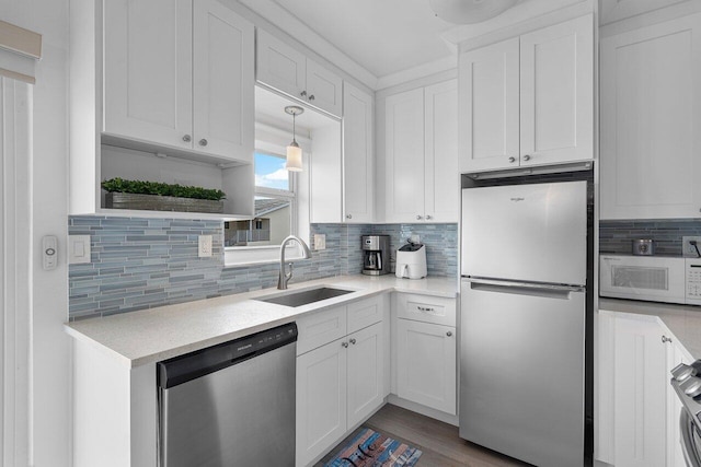 kitchen featuring backsplash, white cabinets, sink, decorative light fixtures, and stainless steel appliances