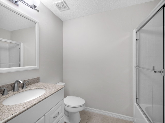 full bathroom with shower / bath combination with glass door, tile patterned floors, toilet, vanity, and a textured ceiling