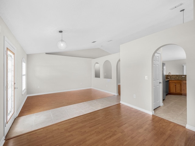 unfurnished room with vaulted ceiling, light wood-type flooring, and plenty of natural light