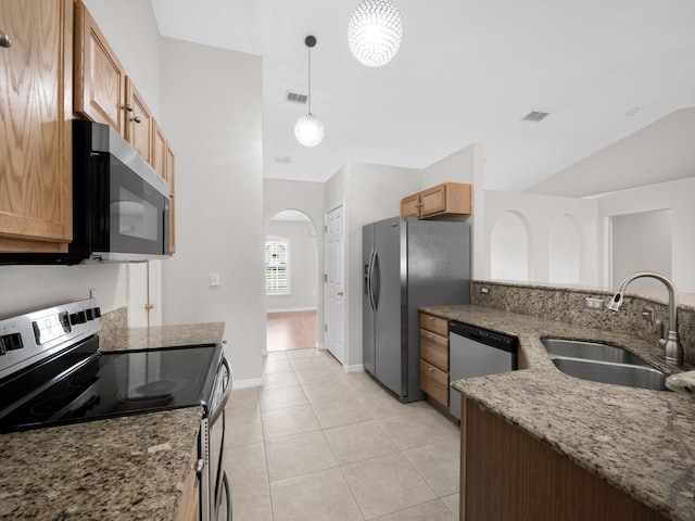 kitchen featuring lofted ceiling, light stone counters, sink, pendant lighting, and stainless steel appliances