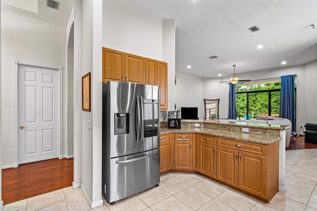 kitchen with light wood-type flooring, kitchen peninsula, and stainless steel refrigerator with ice dispenser