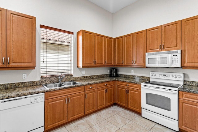 kitchen with sink, light tile patterned floors, dark stone counters, and white appliances