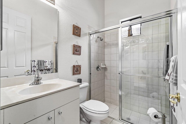 bathroom with tile patterned floors, vanity, toilet, and a shower with door