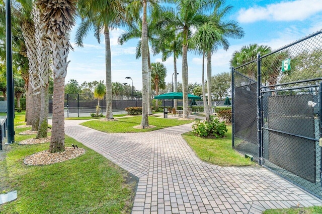 view of property's community featuring a yard and tennis court