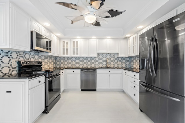 kitchen with a raised ceiling, crown molding, appliances with stainless steel finishes, tasteful backsplash, and white cabinetry