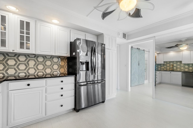 kitchen featuring decorative backsplash, a barn door, stainless steel appliances, and white cabinets