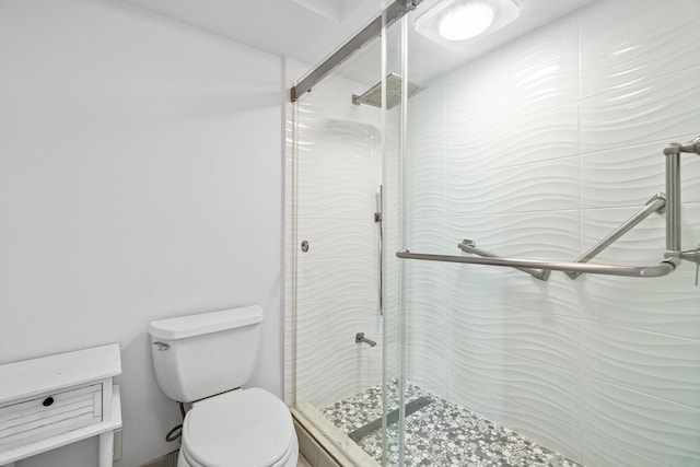 bathroom with a shower with shower door and toilet