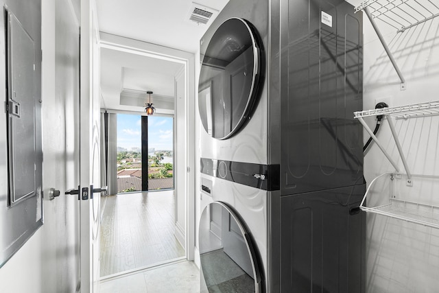 washroom featuring hardwood / wood-style flooring, stacked washer / dryer, and ornamental molding