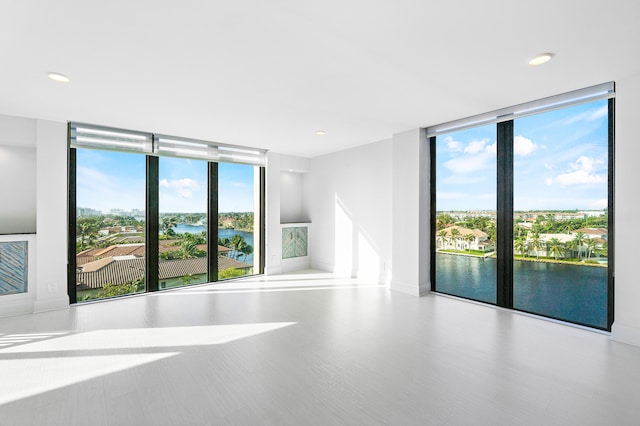 spare room with a water view and a wall of windows