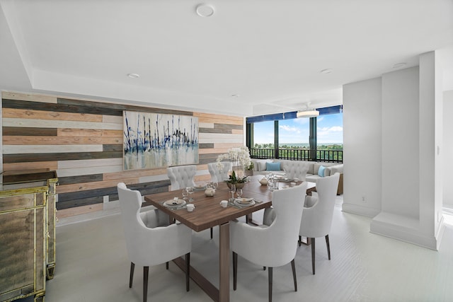 dining area featuring floor to ceiling windows and wooden walls