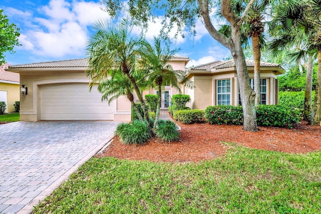 view of front of house with a tile roof, stucco siding, an attached garage, and decorative driveway