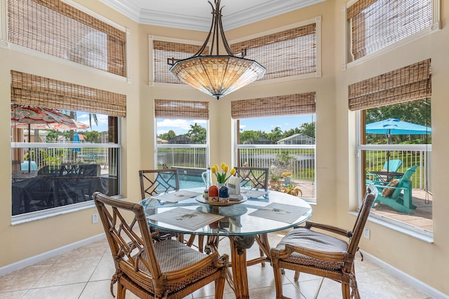 dining room with light tile patterned floors, a towering ceiling, ornamental molding, and baseboards
