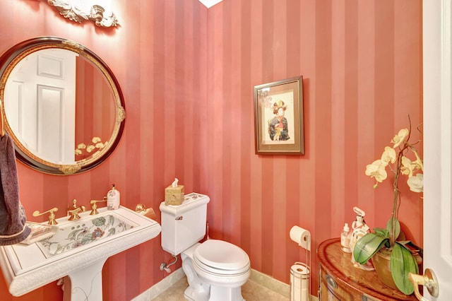 bathroom with toilet, sink, and tile patterned floors