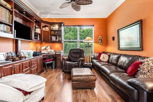 interior space featuring built in desk, ceiling fan, ornamental molding, and light wood-type flooring