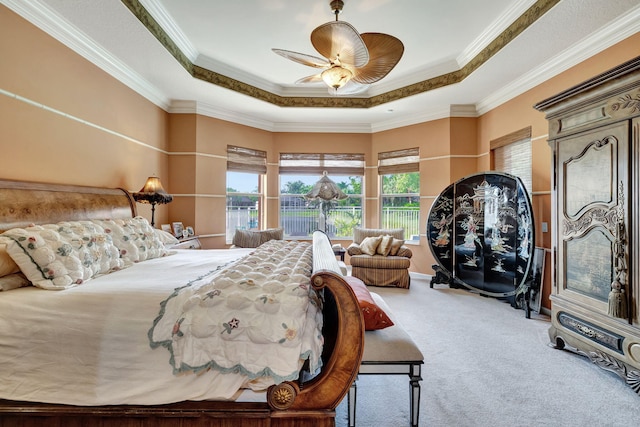 bedroom featuring ceiling fan, a raised ceiling, ornamental molding, and carpet floors