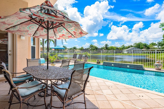 view of pool with fence, a patio, a water view, and outdoor dining area