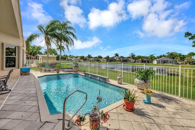 view of pool featuring a patio, fence, a water view, and a residential view