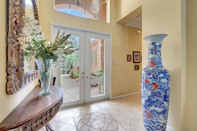 doorway to outside with french doors, a towering ceiling, light tile patterned floors, and baseboards